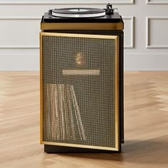 a record player sitting on top of a hard wood floor next to a white wall