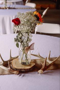 a vase filled with flowers sitting on top of a wooden table next to antlers