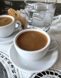 two cups of coffee sit next to each other on a table