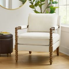 a white chair sitting in front of a window next to a brown footstool