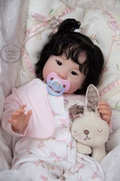 a baby doll with a pacifier in her mouth and a stuffed bunny on the bed