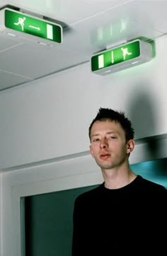 a man standing in front of a green exit sign