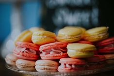 there are many different colored macaroons on the glass platter and one is yellow