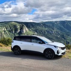 a white car parked on the side of a mountain road