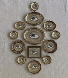 an eye is surrounded by gold frames and other decorative objects on a white cloth background