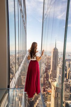 a woman standing on top of a tall building looking out at the city from an observation platform