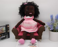 a stuffed doll sitting on top of a brown chair next to a book and flowers