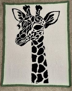 a crocheted giraffe is shown in black and white with green trim