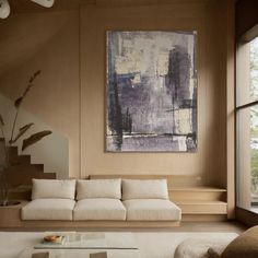 a living room filled with furniture and a large painting hanging on the wall above it