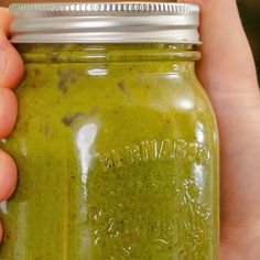 a hand holding a jar filled with green liquid