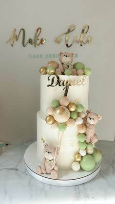 a three tiered cake decorated with teddy bears and green balls on a marble table