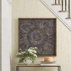 a vase filled with flowers sitting on top of a table next to a stair case