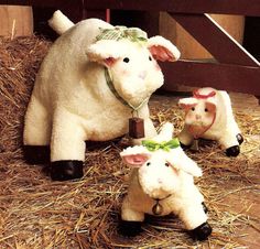 three stuffed sheep are standing in hay next to a fence