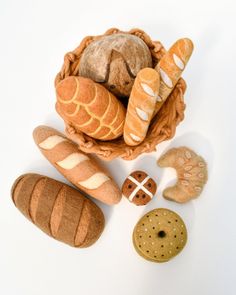 bread and pastries in a basket on a white surface with other items to make it look like they are made out of felt