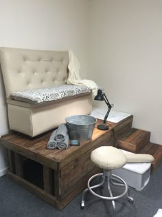 a chair and ottoman sitting on top of a wooden platform next to a wall with white walls