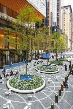 people sitting and standing around in the middle of a courtyard with circular seating areas on each side