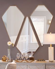 two mirrors are on the wall above a dresser with chairs and a lamp in front of it