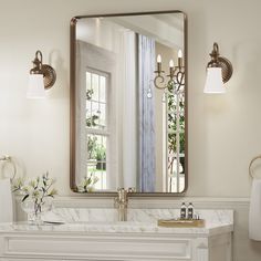 a bathroom sink with a mirror above it next to a white counter top and gold fixtures