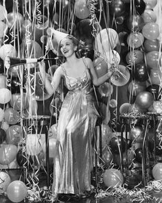 black and white photograph of a woman standing in front of balloon wall with streamers