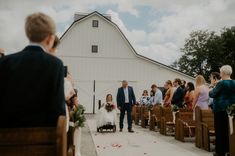 a bride and groom walking down the aisle at their wedding ceremony in front of a barn