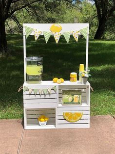 an outdoor lemonade stand is set up in the grass with yellow and green decorations