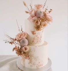 a three tiered wedding cake with pink flowers on the top and bottom, sitting on a silver platter