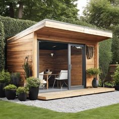 a small wooden shed sitting on top of a lush green field with potted plants