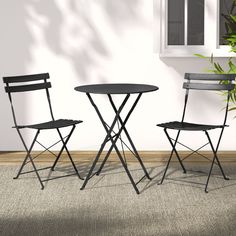 two chairs and a table in front of a wall with a potted plant next to it