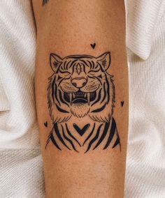 a black and white tiger tattoo on the left leg, with hearts in the background