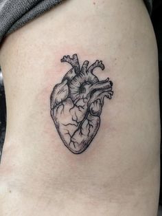 a small black and white heart tattoo on the thigh