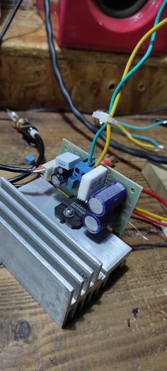 an electronic device sitting on top of a wooden table next to wires and other electrical equipment