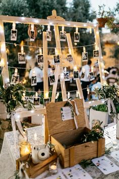 an easel with pictures hanging from it and candles on the table next to it