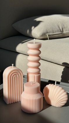 three candles sitting on top of a table next to a couch with pillows in the background