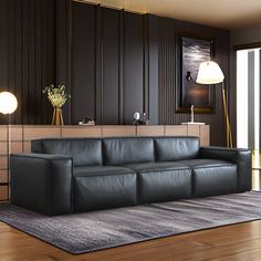 a black leather couch sitting on top of a hard wood floor next to a lamp