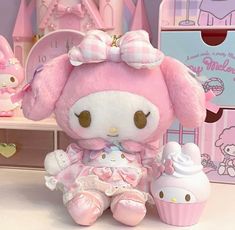 a hello kitty stuffed animal sitting next to a cupcake on a table with other items in the background