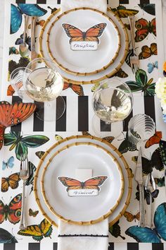 the place setting is decorated with butterflies on black and white striped tablecloth, silverware, and plates