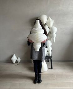 a woman standing in front of a large pile of white vases on the floor