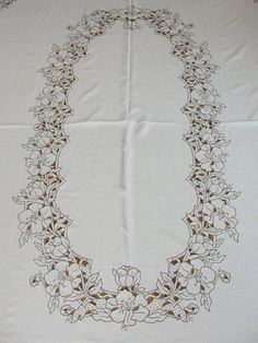 an embroidered tablecloth with flowers and leaves in the shape of a letter o on it