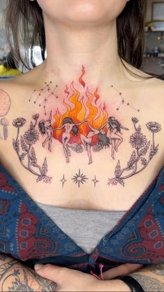 a woman with tattoos on her chest has a fire in the sky above her back