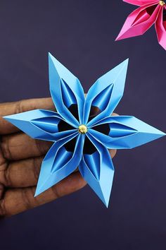 two origami flowers being held by someone's hand