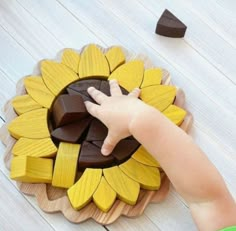 a child's hand touching a wooden sunflower with chocolate pieces in the background