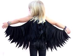 a woman with her arms spread out wearing black wings