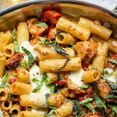 a pan filled with pasta and meat covered in sauce, parmesan cheese and spinach