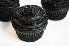 three black cupcakes sitting on top of each other