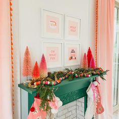 christmas decorations are displayed on the mantel in front of pink curtains and framed pictures