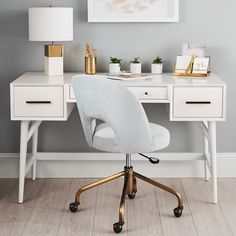 a white desk with two drawers and a gold lamp on the top, in front of a gray wall