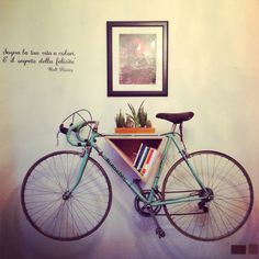 a bicycle leaning up against a wall with a book shelf on the front and bottom