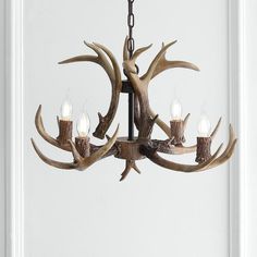 a deer antler chandelier hanging from a white door with candles in it