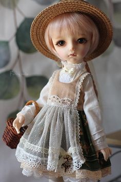 a doll wearing a dress and hat holding a basket