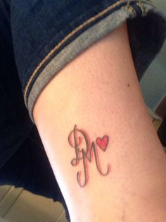 a woman's arm with a tattoo that has the letter m and heart on it